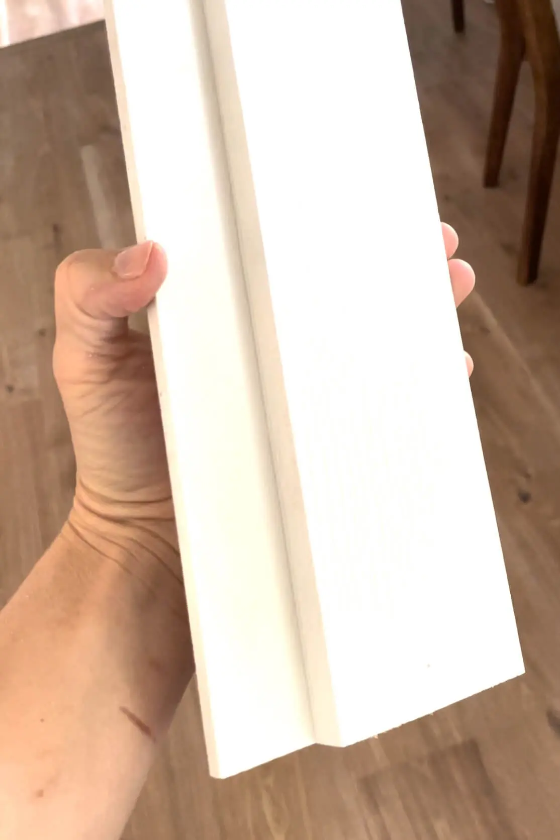 Finished piece of PVC trim cut with a channel for sitting on top of a shiplap backsplash. 